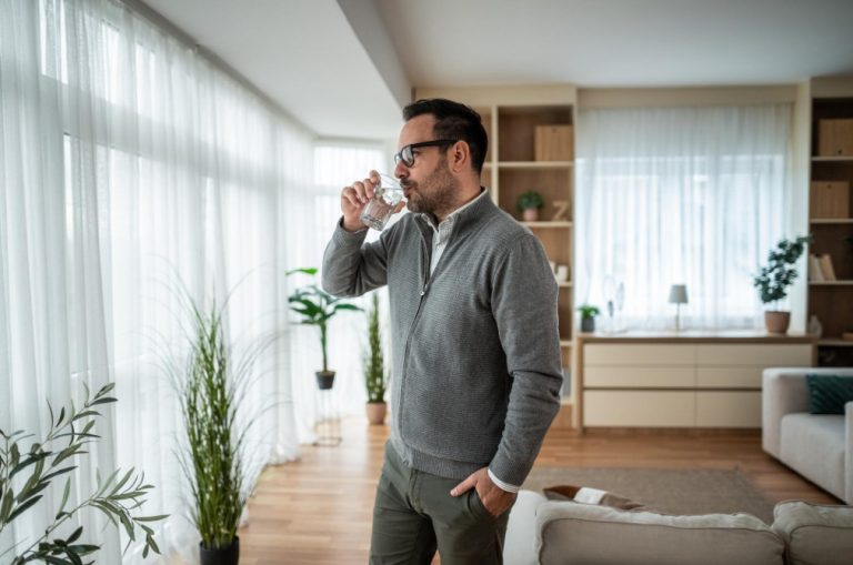 Man drinking coffee in bright roomsemne deshidratare – persoana care bea apa